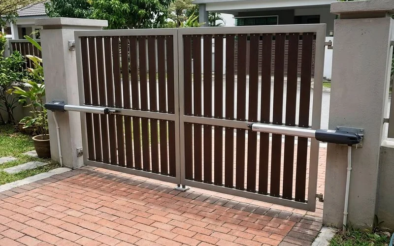 Completed swing arm autogate installation showing both motor arms mounted on pillars with control panel box